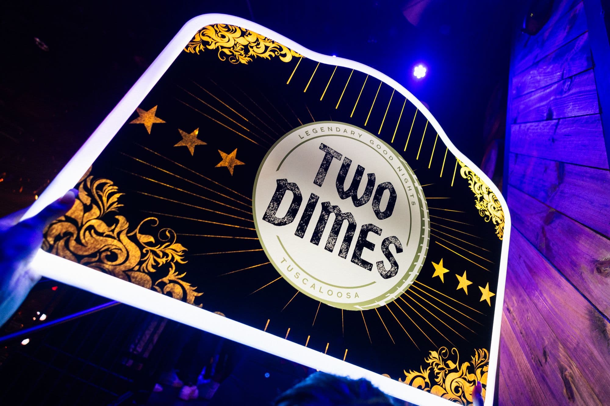 The lit Two Dimes VIP sign carried over a packed floor